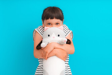 cute child girl hugs her favorite stuffed toy, a cat loaf, a pillow toy