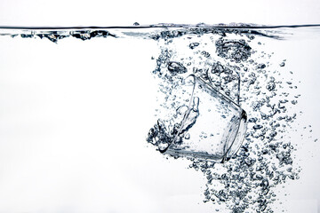 transparent glass dropped into the water on a white background