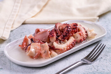 Octopus salad. Mediterranean cuisine delicacies. Octopus arms with olive oil on stone background. Close-up