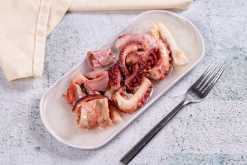 Octopus salad. Mediterranean cuisine delicacies. Octopus arms with olive oil on stone background. Close-up
