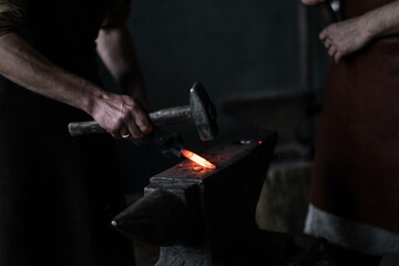 blacksmith hitting a red-hot iron with a hammer