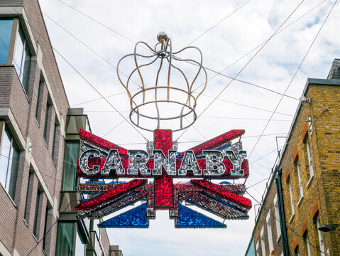 London, UK, June 3rd 2022: Carnaby Street Decorations. To Celebrate The Queens Platinum Jubilee, 70 Years In Service. A Giant Union Jack Glitter Sign Flag With Royal Crown Above. Bank Holiday.