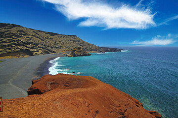 Beautiful secluded lagoon surrounded by impressive rugged weathered cliffs, different colors,red rock,  empty deserted black sand beach - El Golfo, Lanzarote