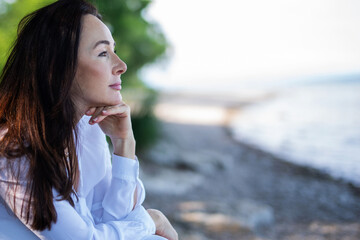 Attraktive und sympathische Frau in weißer Bluse an einem See, Schönheit und Entspannung 