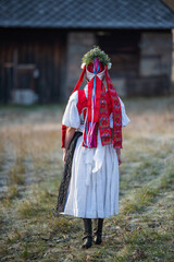 Woman dressed in traditional folk costume. Slovak costume in autumn nature. Old country cottage in...