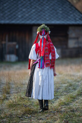 Woman dressed in traditional folk costume. Slovak costume in autumn nature. Old country cottage in the background. Details of Slovak costume from Detva and Hrinova