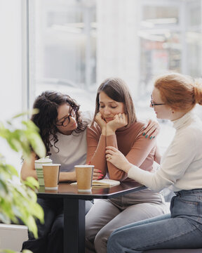 friendship and support in a difficult situation, three female friends discuss the problem and support each other, depression and sadness in a woman, group psychotherapy and support from friends and