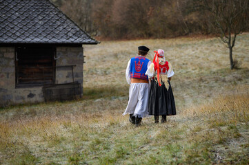 A couple dressed in traditional folk costume. Slovak costume in autumn nature. Old country cottage...