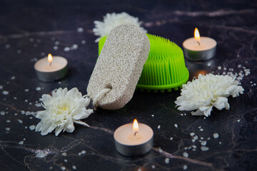 Cleaning foam and a green washcloth lie on a dark background surrounded by scattered salt, white flowers and burning candles. High quality photo