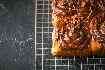 cinnabon buns with cinnamon, pecan and cream cheese on a black background. Flat lay. Close up