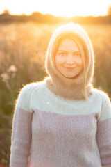 Portrait Of Young Pretty Caucasian Happy Girl Woman In Woolen Jacket Blouse And Brown knitted bonnet Posing In Early Spring Forest In Sunny Day. Enjoy Outdoor Nature. beautiful young woman smiling
