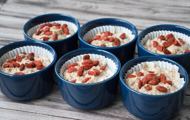 Making Almond Muffins with Goji Berries. Raw Dough in Forms on a Wooden Table