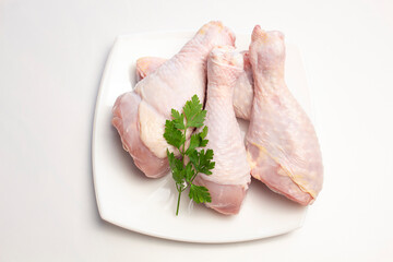 raw chicken legs in a plate on a white background