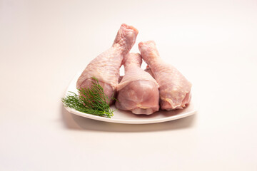 raw chicken legs in a plate on a white background