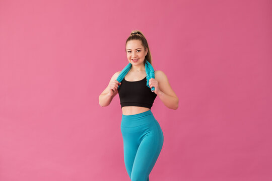beautiful young sports girl with a blue towel on her shoulders on a pink background, space for text, portrait of a girl in sportswear, healthy lifestyle.