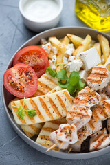 Slices of grilled halloumi cheese, souvlaki skewers and potato fries with feta, vertical shot, close-up, selective focus