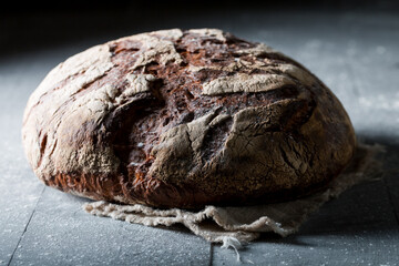 Bread with whole grains on dark table with flour