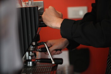  A professional barista prepares coffee in a carob coffee machine. Favorite job in the restaurant industry.A small coffee business. Makes espresso, Americano with a takeaway.