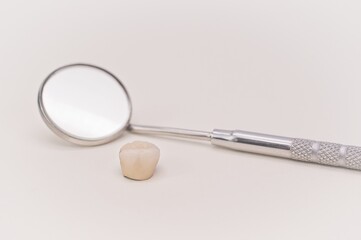 dental ceramic crown and mirror on a white desk - tools and professions