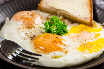 Fried eggs and bread for breakfast on a gray background.
