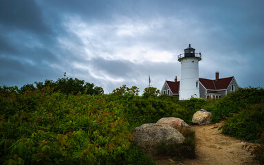 Fototapeta na wymiar Dramatic weather condition over the lighthouse on the green hilltop in Woods Hole on Cape Cod