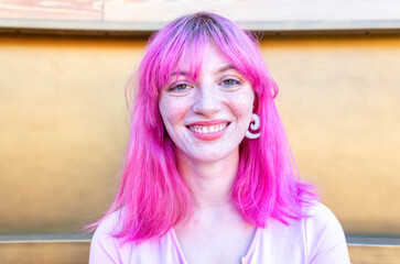 close up portrait of alternative woman withpink hair hanging out chilling and smiling standing...