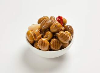 grilled green olives in oil, pitted, with red hot pepper and garlic in a white bowl on a light background, side view