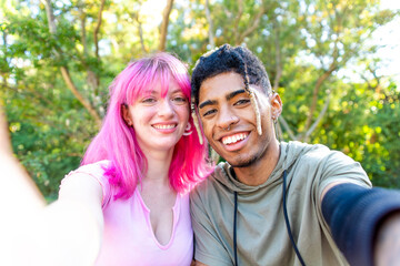 alternative diverse couple hanging out in a park making a pov selfie portrait holding smartphone on...