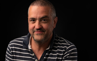 Smiling man with one eyebrow raised on a black background with copy space