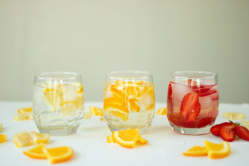 Three refreshing summer drinks with lemon, strawberry and orange