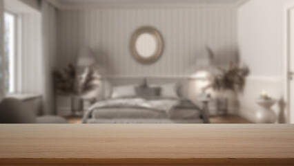 Fototapeta na wymiar Empty wooden table, desk or shelf with blurred view of classic white bedroom, wallpaper, bed with duvet, side tables, armchair and decors, modern interior design concept