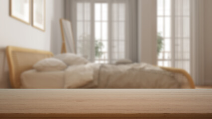 Fototapeta premium Empty wooden table, desk or shelf with blurred view of contemporary white bedroom, rattan bed with duvet, frames and mirror, windows, modern interior design concept