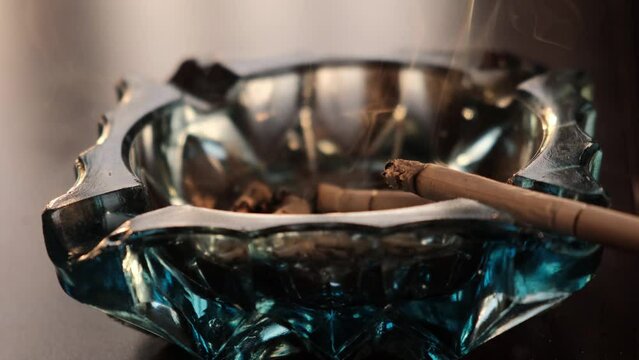 Cigarette smoldering in an ashtray close-up view