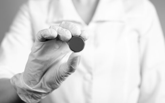 Doctor holding pill. Erroneous medication prescription, wrong dosage or medical decision, malpractice, tablets side effects concept. Black and white. High quality photo