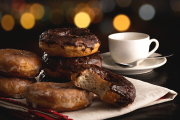 Donuts in white plate on table with cup of coffee with bokeh lights