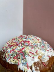 Vertical cropped shot of a paska easter cake covered with white frosting and colorful sprinkles