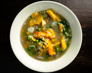 Vegetable variety soup in white plate on wooden table