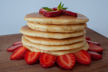 Pancakes with close up view, fresh strawberries and maple syrup on. Selective focus and isolated on white background.