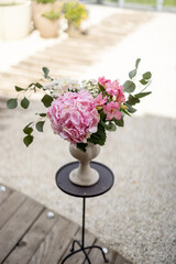 Composition of hydrangea flower with pink blossom in beautiful vase on table in garden