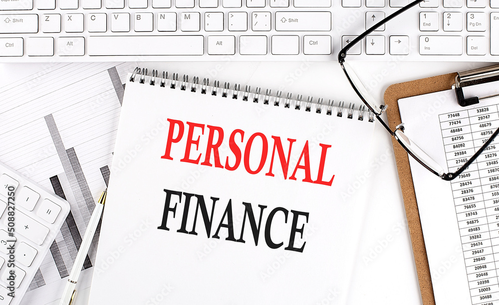 Poster text personal finance on office desk table with keyboard, notepad and analysis chart on white backgr