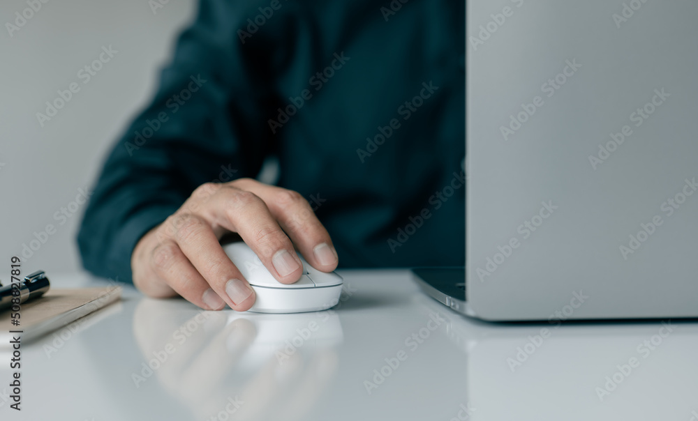 Poster A man hand holds a computer mouse and types on a laptop keyboard.