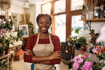 Happy African American flower shop owner standing with her arms crossed and looking at camera.