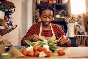 African American woman making bouquet of tulips at flower workshop.