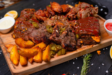 cold cuts with fried potatoes on a dark background