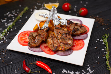 grilled meat on a bone. freshly sliced tomatoes and onions