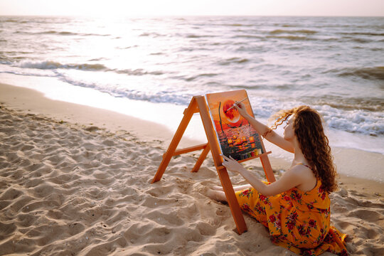 Young female artist drawing the picture at the beach. Hobby and leisure concept. Talent and creativity. Canvas Painting.