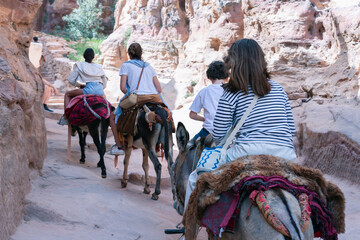 Tourist using a Bedouin donkey for transport in Petra Jordan. Descends stairs next to other...