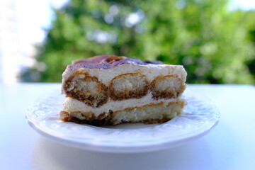 appetizing piece of tiramisu, popular Italian dessert, a classic recipe made from Mascarpone cheese and Savoiardi biscuits, calorie sweets concept, unhealthy food, homemade baking