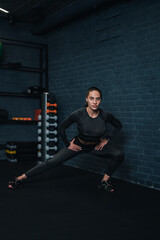 Fototapeta na wymiar girl athlete is exercising trx in the gym. dark background