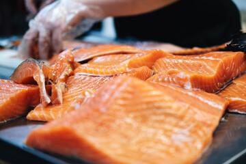 a gloved cook slices juicy salmon steaks